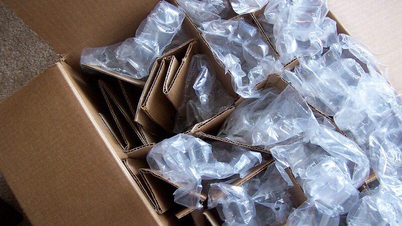 Open cardboard moving box fitted with dividers and air-pillow cushioning protecting fragile items