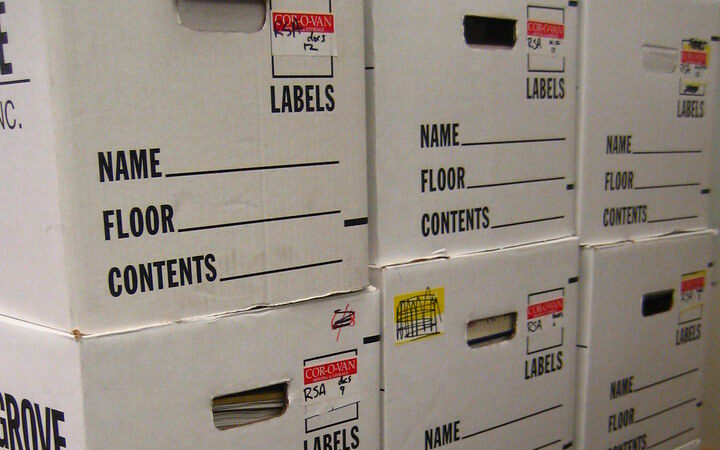 Stacked office relocation boxes labelled with name, floor and contents fields