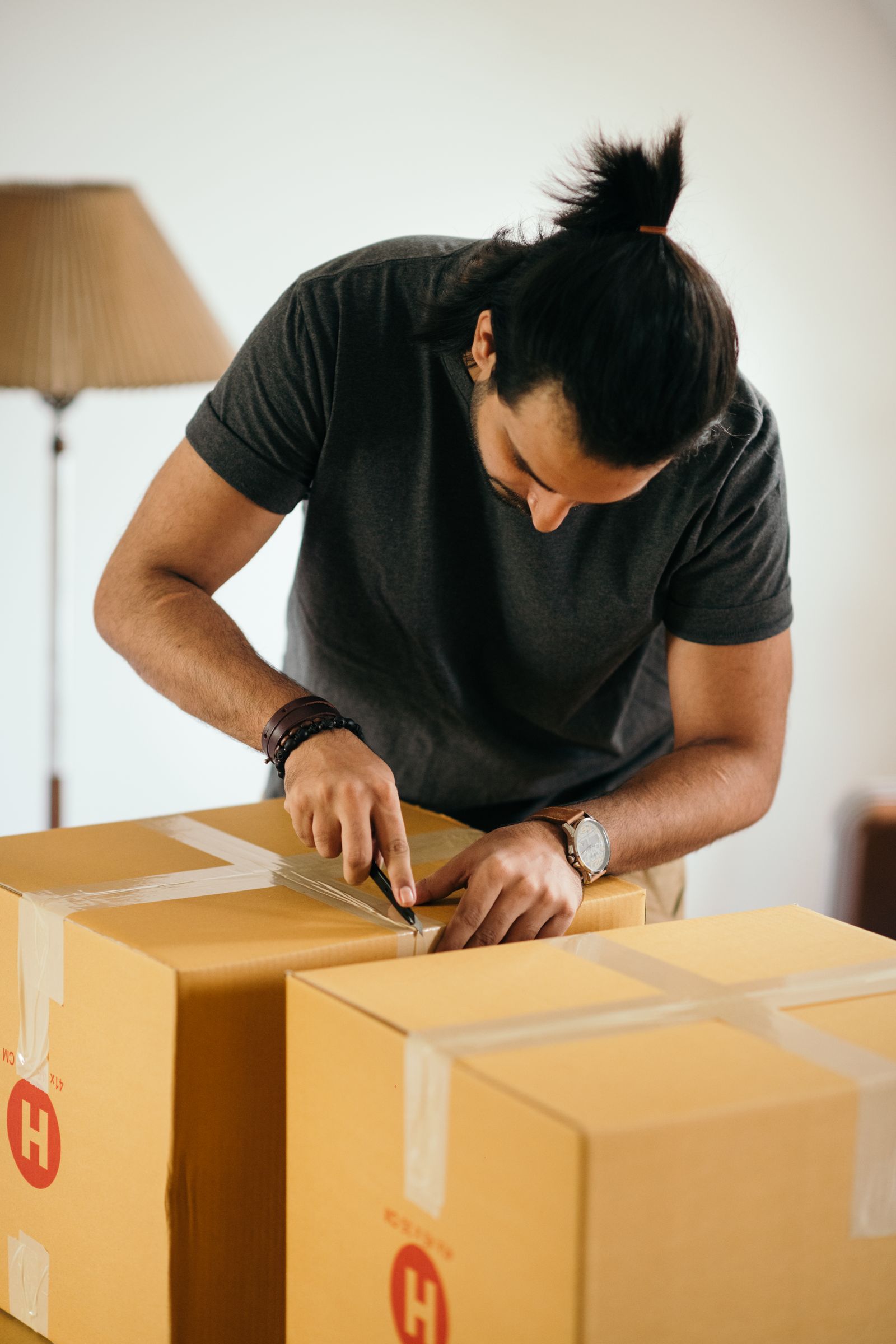 Mover sealing a cardboard packing box with tape during a household move
