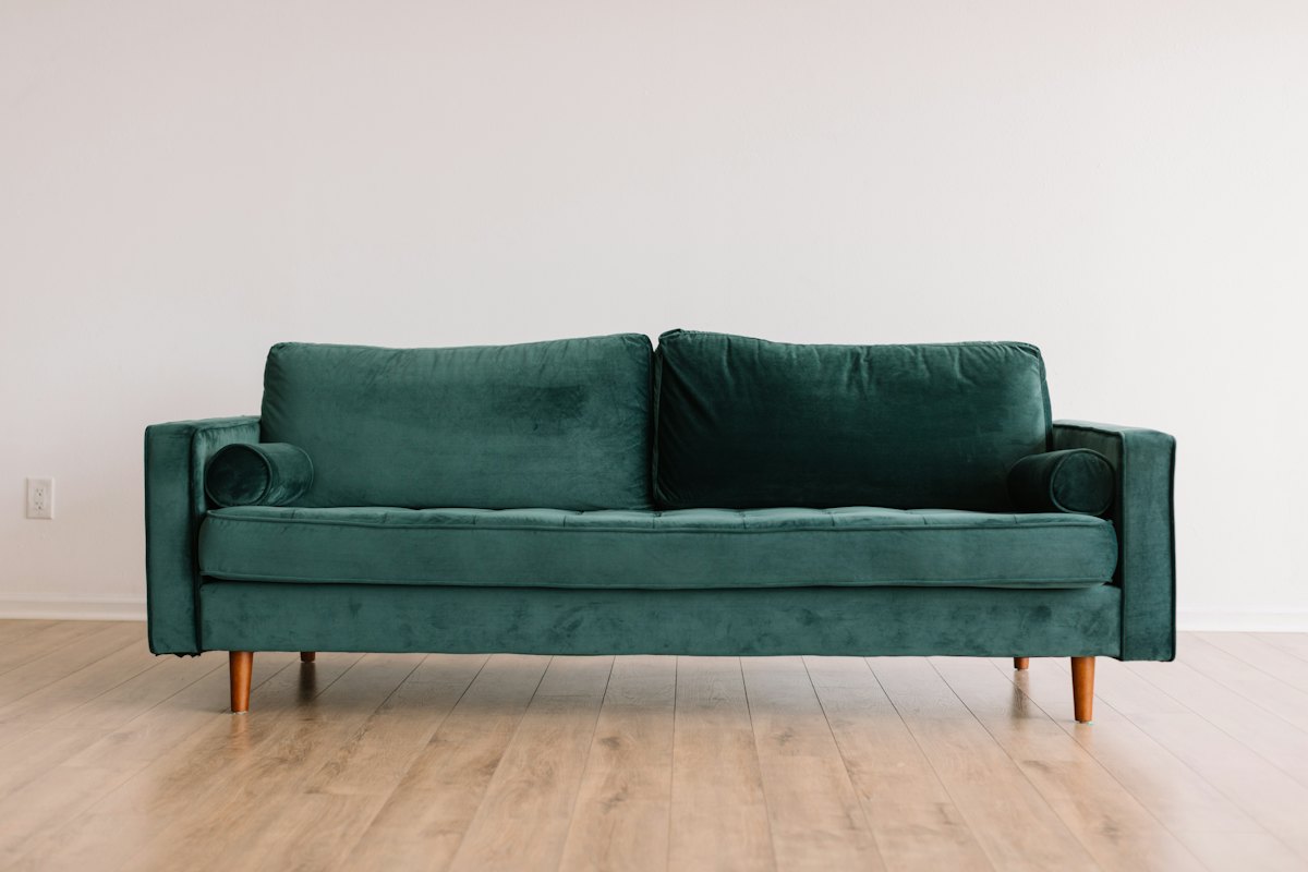 Green velvet two-seater sofa photographed front-on — household furniture removals in Christchurch